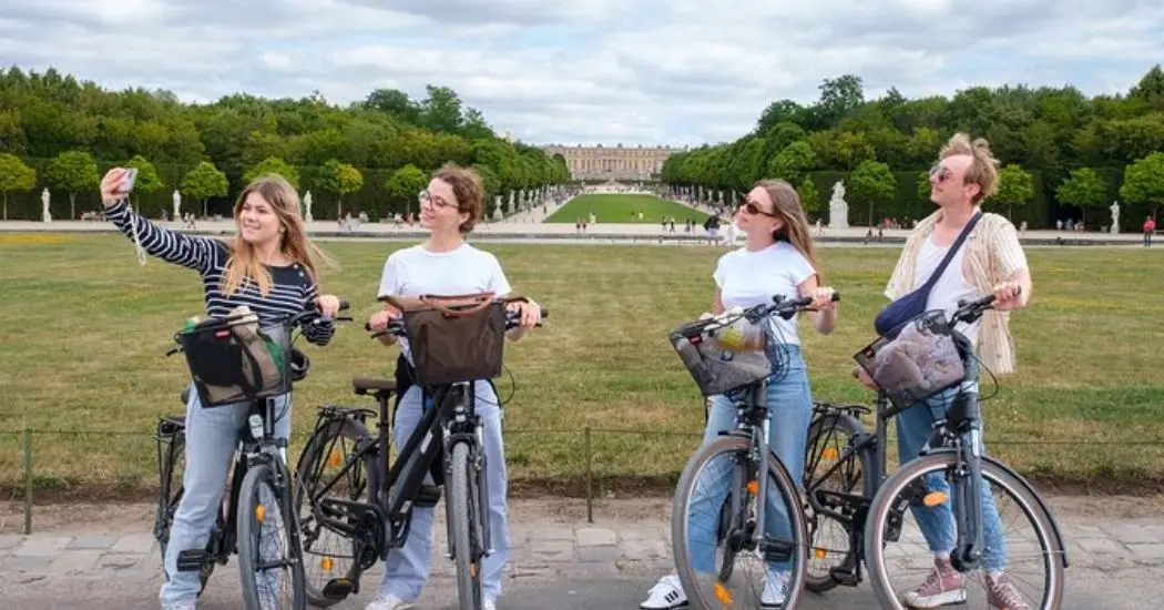Tourists in bike tour taking selfies in the beautiful backgroung view of the Palace of Versailles